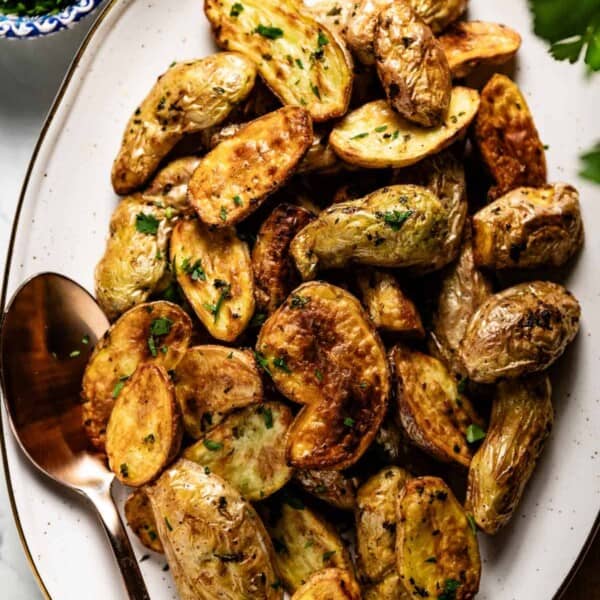 Fingerling potatoes cooked in the air fryer on a plate with a spoon on the side.