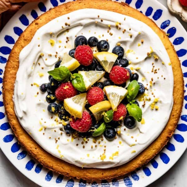 Almond flour lemon cake garnished with whipped cream and berries from top view