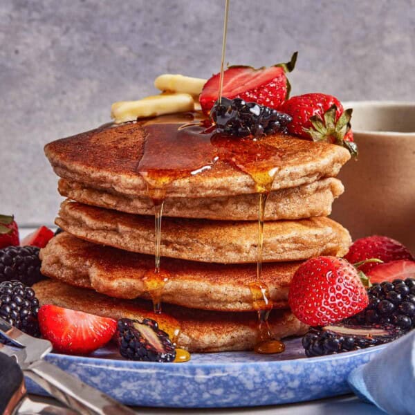 Almond flour pancakes stacked and being drizzled with maple syrup.