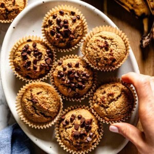 Person taking a muffin from a plate from the top view.