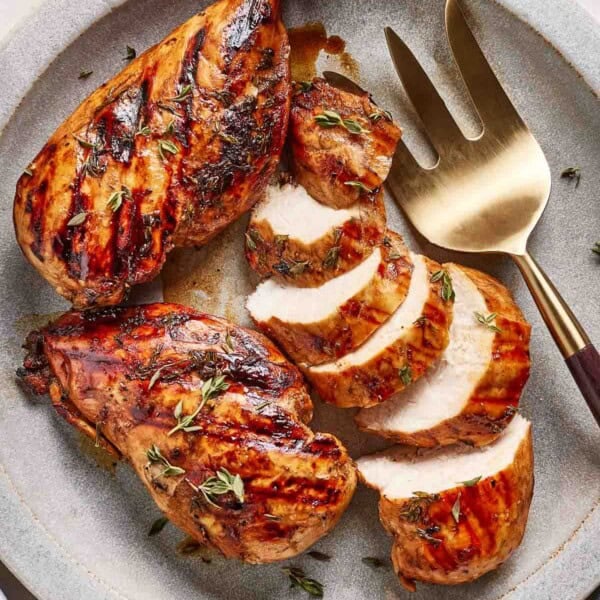 Balsamic marinated grilled chicken on a plate from the top view.