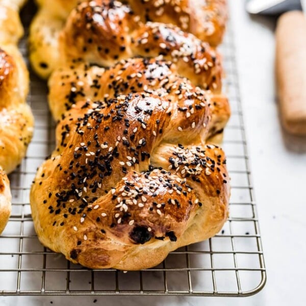 Challah bread placed on a wire rack with a knife on the side
