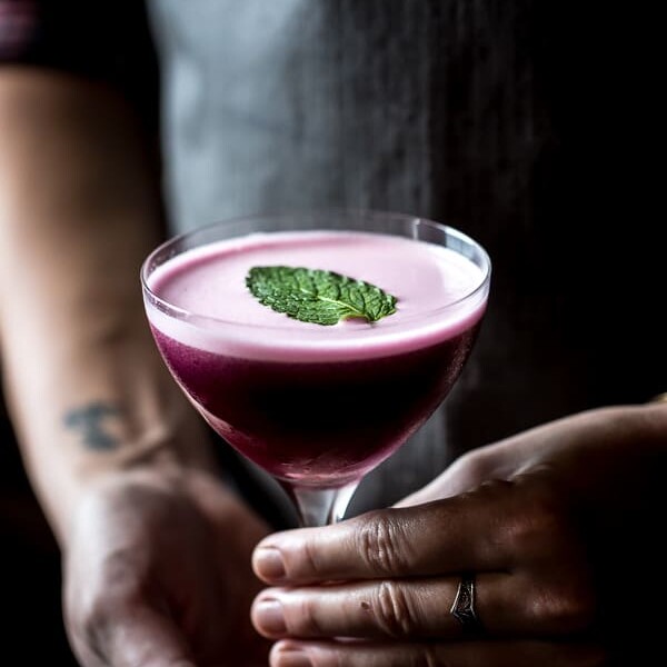Person holding a glass of Blueberry, Dark Cherry and Calvados Cocktail