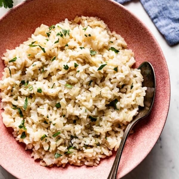 Brown jasmine rice in a plate with a spoon on the side.