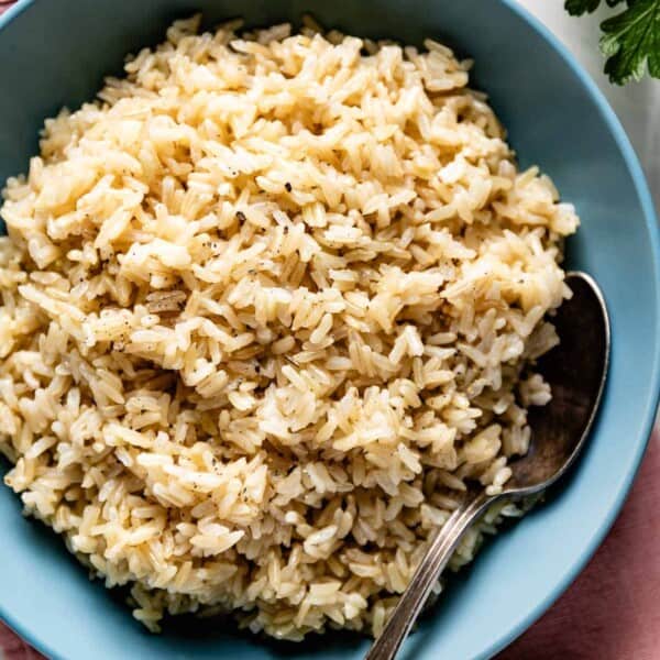 Cooked brown jasmine rice in a bowl with a spoon on the side.