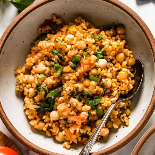 Bulgur pilaf in a bowl with a spoon on the side from top view.