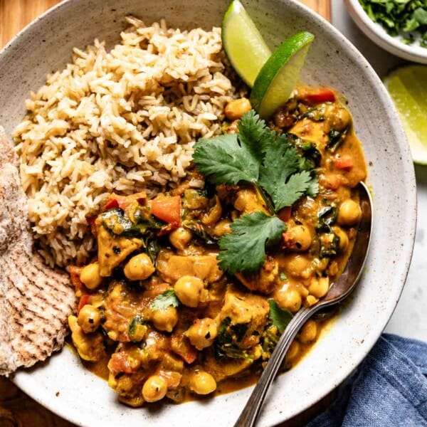 Chicken chickpea curry in a bowl served with naan and rice from the top view.