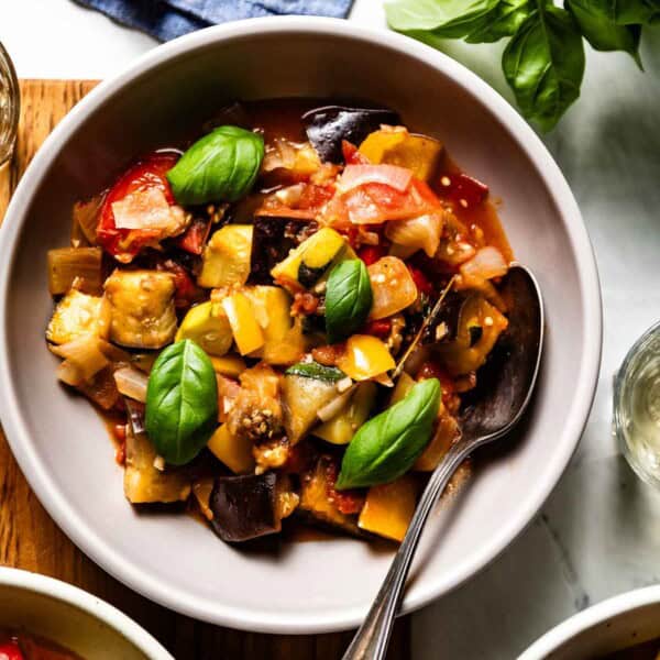 A bowl of ratatouille garnished with basil from the top view.