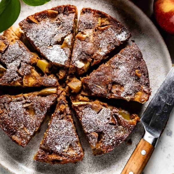 French Apple Cake sliced with a knife on the side.