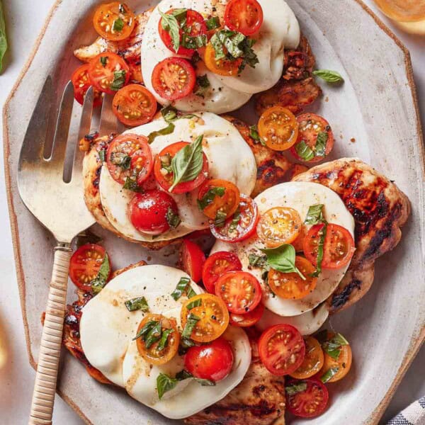 Grilled Caprese chicken on a plate garnished with basil.