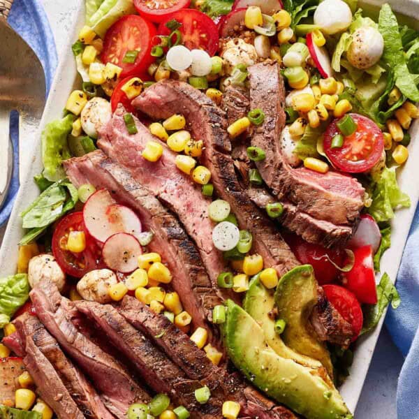 Grilled flank steak salad garnished with corn from the top view.