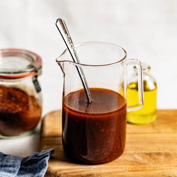 Harissa Vinaigrette in a jar with a spoon in it from the front view.