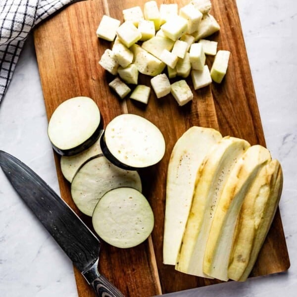 Eggplant cut into various shapes on a cutting board.