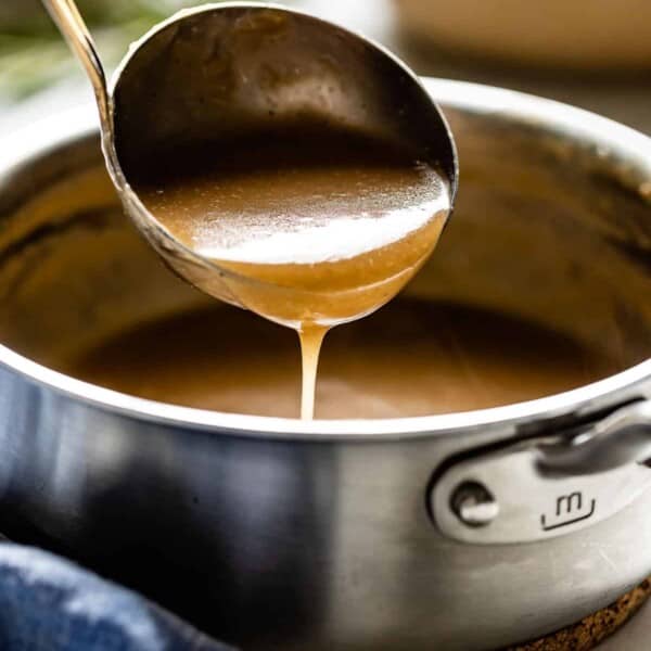 A gravy made from beef broth in a ladle from the side view.