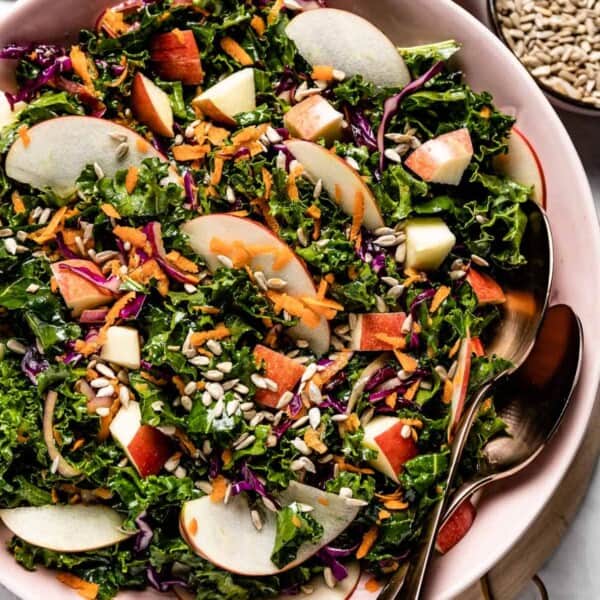 Kale Apple Slaw in a bowl with two tablespoons on the side.