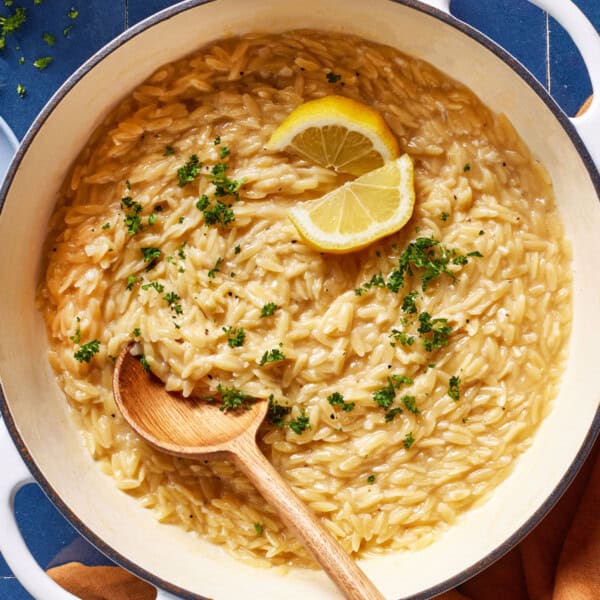 Lemon orzo in a pot garnished with fresh lemon slices.