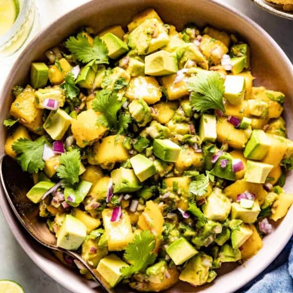 mango avocado salad in a bowl with a spoon on the side