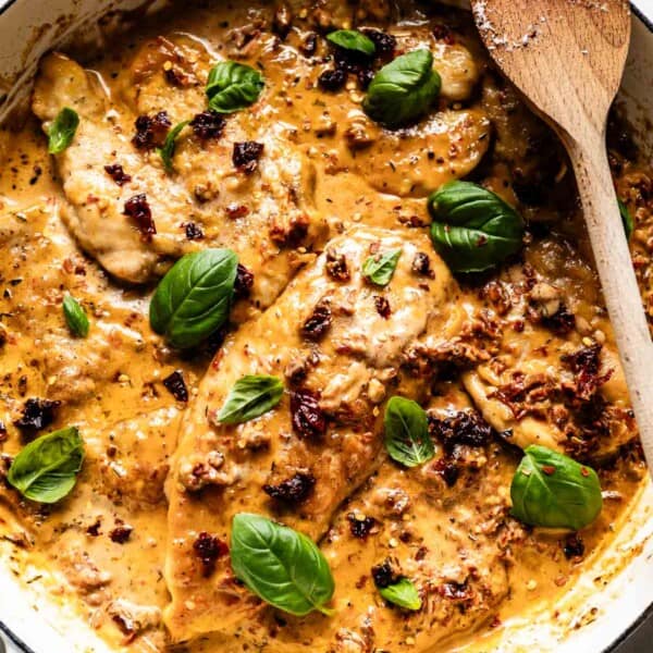 Marry Me chicken in a skillet with a wooden spoon on the side.