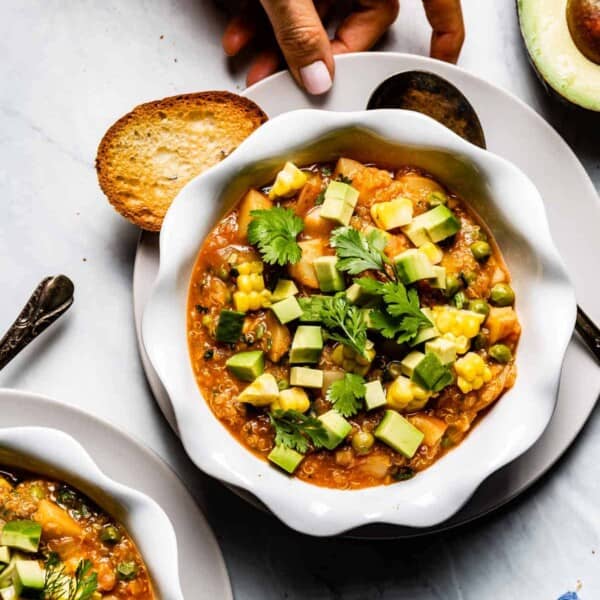 a bowl of quinoa chili served by a person from the top