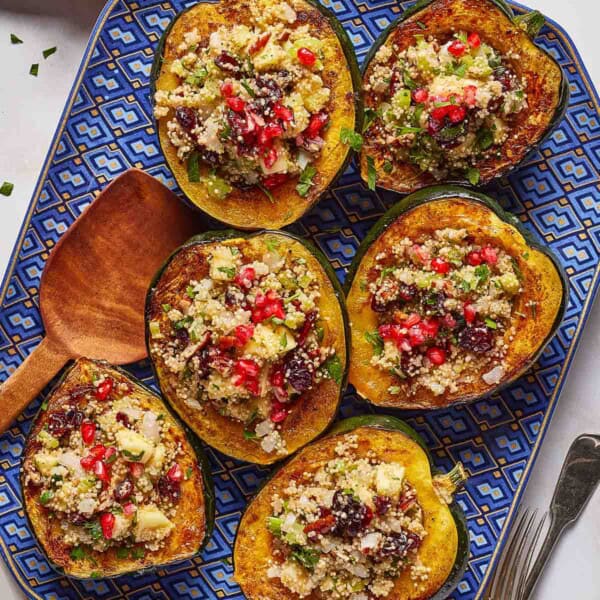 Quinoa stuffed acorn squash halves garnished with pomegranate arils.