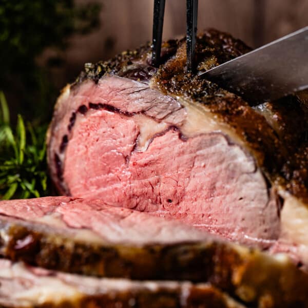 Reverse sear prime rib is being sliced by a person.