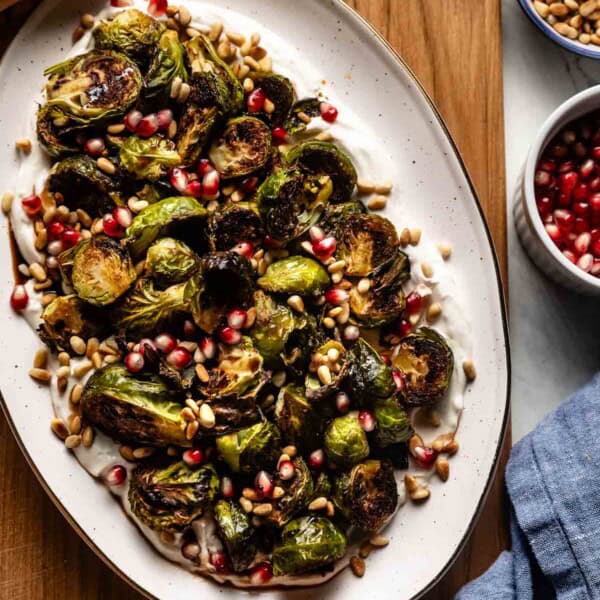 Roasted Brussel sprouts served over tahini yogurt sauce on a plate.