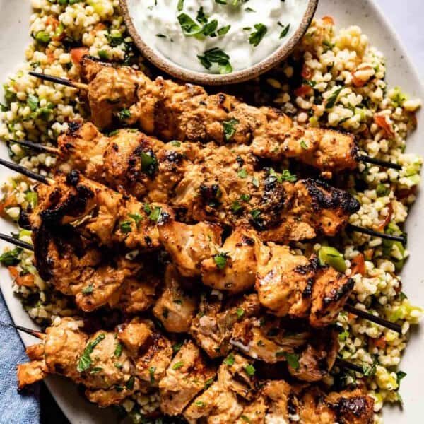 Shish tawook served with yogurt sauce over a bed of tabbouleh from the top view.