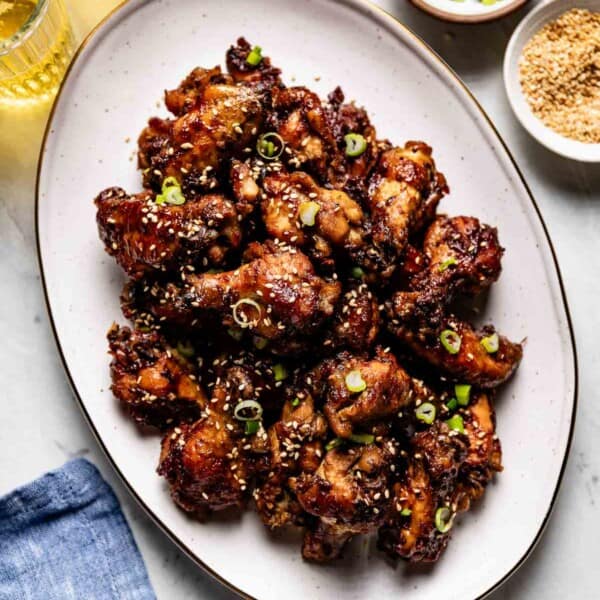 Slow cooker sticky chicken wings on an oval plate from the top view.