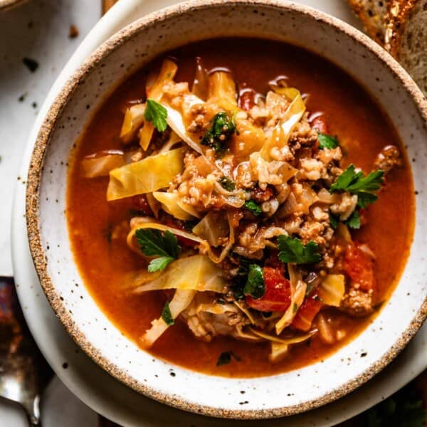A bowl of stuffed cabbage soup with a spoon on the side.