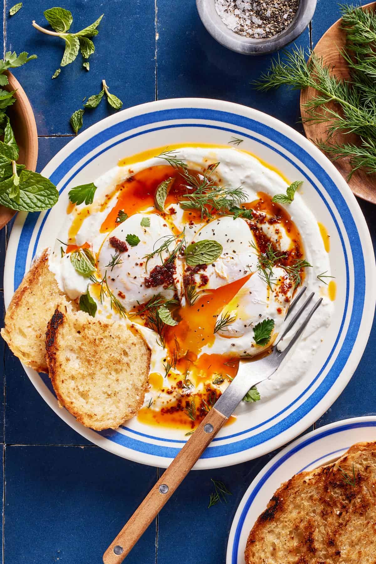 Turkish eggs (aka cilbir) on a plate from the top view with two slices of bread on the side.