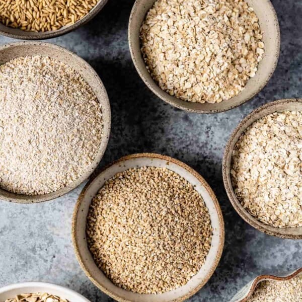 Different types of oats placed in bowls from the top view.