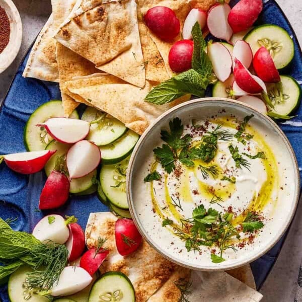 Whipped feta dip with vegetables and pita on a serving platter.